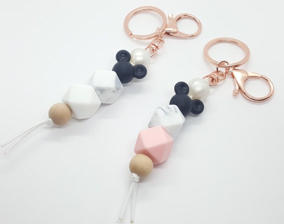 Disney family silicone beaded keychains. Features mouse ears and a gray marbled bead with a choice of black, beige, blue, white, or pink. Disney family silicone beaded keychains. Features mouse ears and a gray marbled bead with a choice of black, beige, blue, white, or pink.