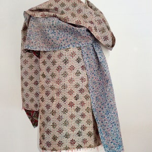May include: A beige, blue, and red kantha quilt scarf with a geometric pattern. The scarf is draped over a white mannequin.