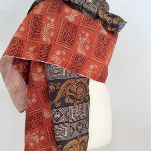 May include: A reversible silk scarf with a red and black paisley pattern. One side features a geometric design with a floral motif. The other side features a paisley pattern with a floral motif.