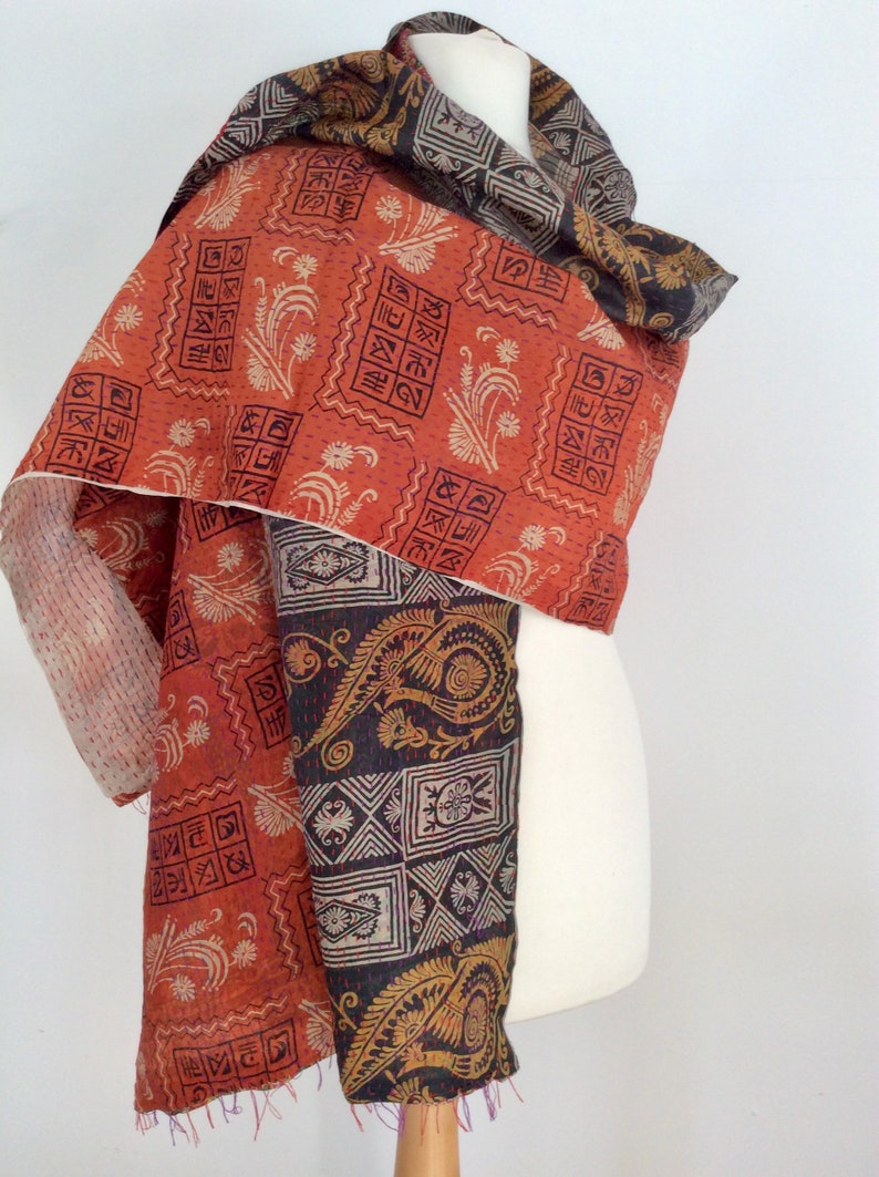 May include: A reversible silk scarf with a red and black paisley pattern. One side features a geometric design with a floral motif. The other side features a paisley pattern with a floral motif.