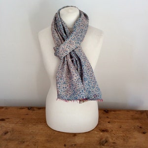 May include: A light blue and pink patterned scarf with a white background. The scarf is tied around a white mannequin.