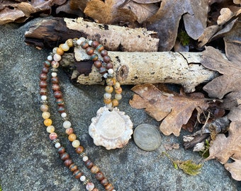 Antler burr pendant hanging from a strand of natural crazy lace agate and Tibetan agate beads with brass accents.