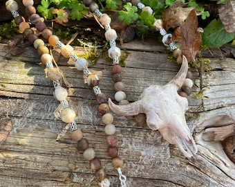 American Bison replica miniature skull hung from a strand of different sizes, shapes and colors of petrified wood beads.