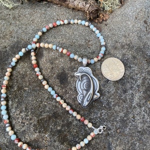 Koi fish pendant hung from a strand of sea sediment jasper beads with silver accents.