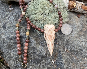 Raven skull carved in buffalo bone and hung from a strand of brown jasper beads.