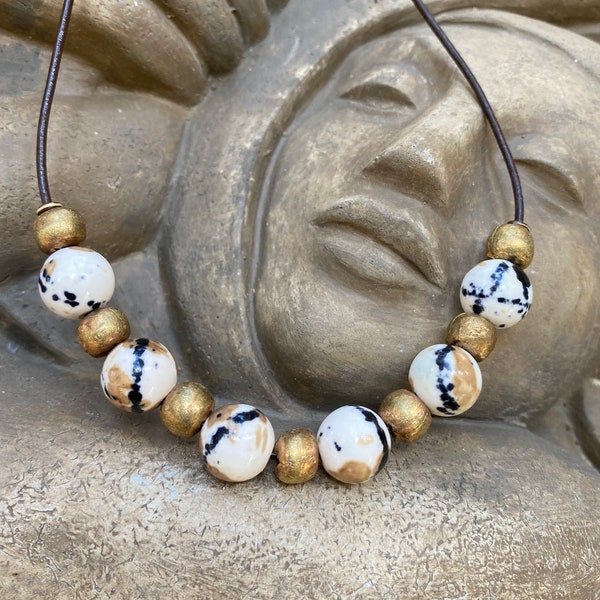 Necklace of Milk Coffee Flower Jade beads with brass spacers on brown leather cord.