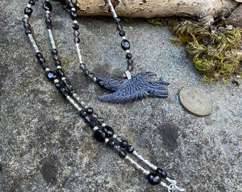 Flying raven pendant carved in ethically sourced horn and hung from a strand of onyx and faceted quartz beads with silver tone accents.