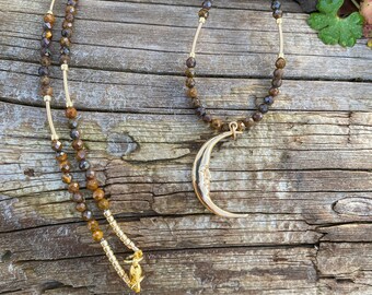 Delicate crescent moon with face hanging from a strand of tiny faceted bronzite beads with gold accents.