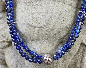 Three strand necklace of different sizes and shades of Lapis with silver accents.