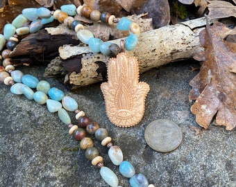 Hamsa hand carved in ethically sourced bone and hung from strand of amazonite nugget beads and jasper beads with copper accents.