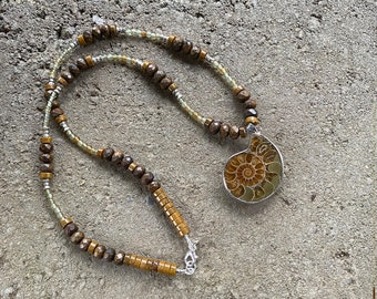 Ammonite pendant hung from a strand of bronzite, jasper and agate beads with silver accents.