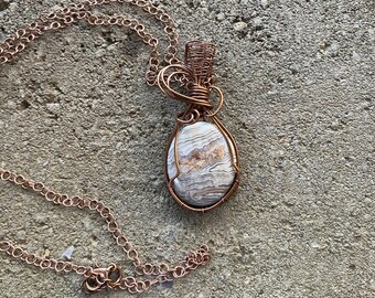 Crazy lace agate pendant wire wrapped/weaved with copper wires. Free copper plated chain included.