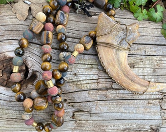 Utahraptor claw replica, actual size, hung from a strand of tiger's eye and Red Creek jasper beads with brass accents.