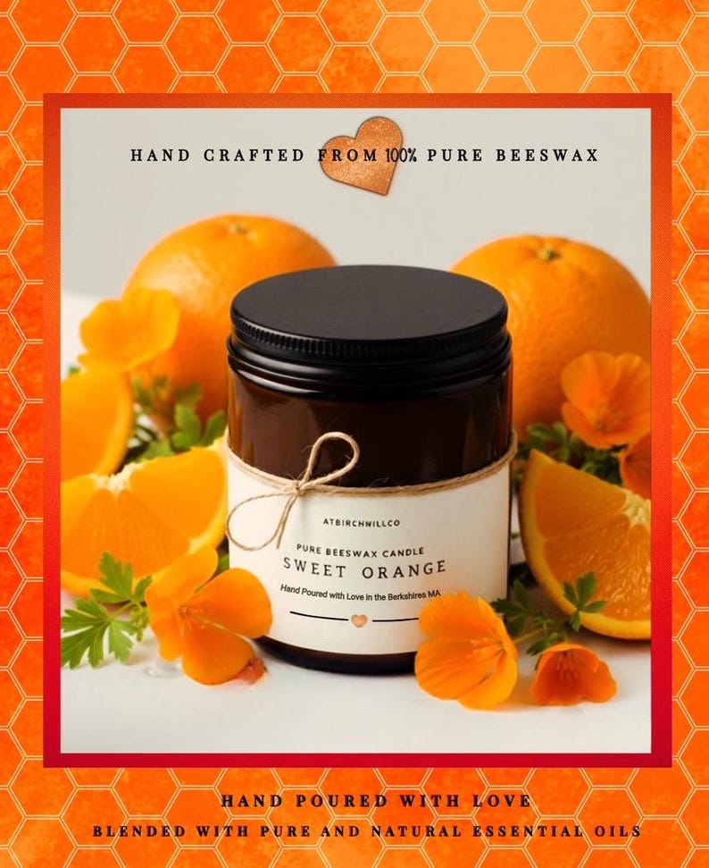 May include: A dark amber glass jar candle with a black lid and a white label reading ATBIRCHWILLCO PURE BEESWAX CANDLE SWEET ORANGE. The label is tied with twine and surrounded by fresh orange slices and bright orange flowers on a white surface.