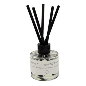 Op de afbeelding: Een diffuser van helder glas met zwarte rietjes en een wit label met de tekst "savon du marché français" en de geuren: lavendel, eucalyptus, perenbloesem, lelietje-van-dalen en fresia.
