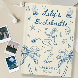 May include: A white cover with blue illustrations of a mermaid, palm trees, and stars. The text "Lily's Bachelorette" is written in blue cursive. The text "Cheers! Miami Beach, FL May, 2025" is written in blue.