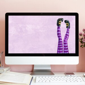 Puede incluir: Un monitor de computadora con un fondo morado claro y un par de piernas de bruja con medias rayadas de color morado y blanco y zapatos negros que sobresalen de la parte inferior de la pantalla.
