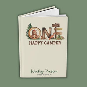 Puede incluir: Un libro de color crema con una ilustraci&oacute;n marr&oacute;n y verde de la palabra "UNO" con un oso, un zorro y una tienda de campa&ntilde;a. El texto "HAPPY CAMPER" est&aacute; debajo de la ilustraci&oacute;n. El libro tiene el nombre "Wesley Preston" y el texto "PRIMER CUMPLEA&Ntilde;OS" en la parte inferior.