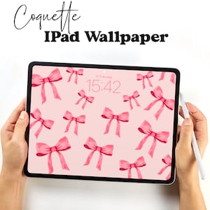 May include: A pink iPad with a pink bow wallpaper and the time 15:42 displayed on the screen. The iPad is being held by a person's hands.