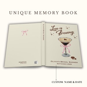 May include: Open memory book with the text "Love is Brewing" and a watercolor illustration of a cocktail with a pink ribbon. The book is cream-colored with the text "Olivia's Bridal Shower September 2025".