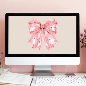 May include: A pink bow with a white ghost pattern on a computer screen. The bow is tied with a white ribbon and has a white lace trim.