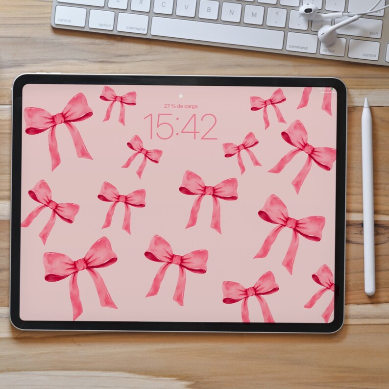 May include: A pink iPad screen with a pink bow pattern and the time 15:42 displayed on the screen. The text "27% de carga" is also displayed on the screen.
