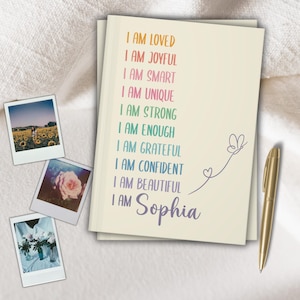 Pu&ograve; includere: Un taccuino color crema con le parole "I AM LOVED" a "I AM BEAUTIFUL" e "I AM Sophia" in colori arcobaleno. Sono presenti anche una penna dorata e tre foto in stile polaroid.