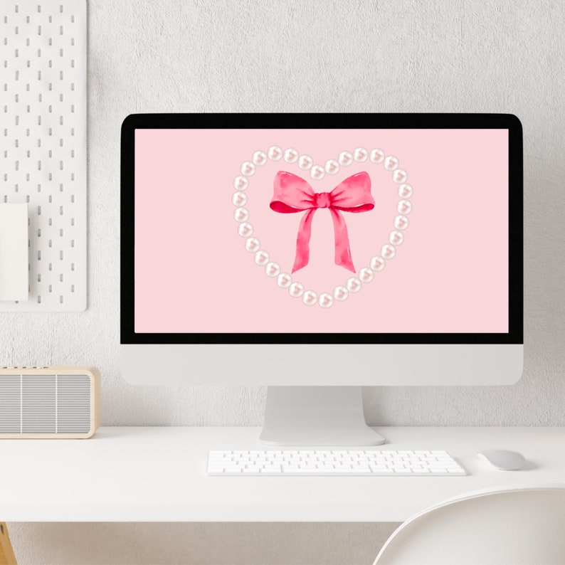 May include: A pink computer desktop background with a white pearl necklace in the shape of a heart with a pink bow in the center.