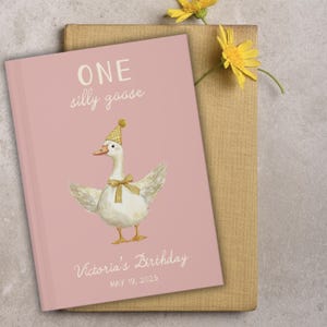 Puede incluir: Un libro rosa con la frase "ONE silly goose" y una ilustraci&oacute;n de un ganso con gorro de fiesta y pajarita. El libro tambi&eacute;n incluye el texto "Victoria's Birthday MAY 19, 2025".