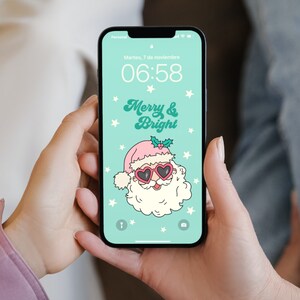 May include: A smartphone displaying a Christmas-themed wallpaper with a cartoon Santa Claus wearing pink heart-shaped sunglasses and the text "Merry & Bright". The time on the phone is 06:58.