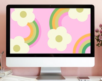 May include: A computer monitor displaying a pink background with white flowers and rainbow arches. The monitor is on a white desk with a keyboard and a mobile phone.
