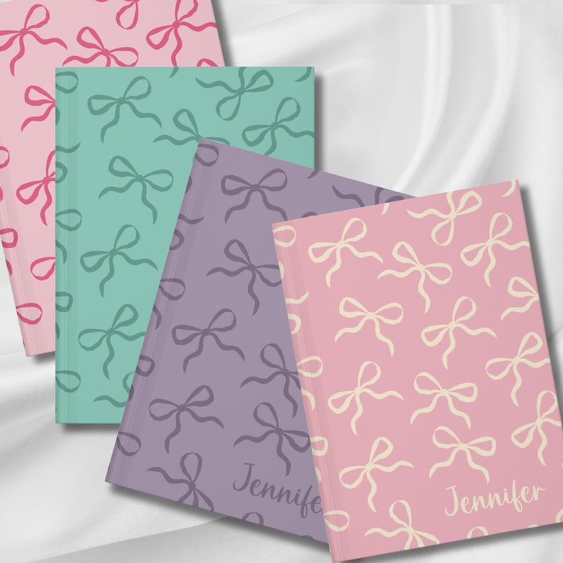 May include: Three notebooks with different colored covers and a bow pattern. The covers are pink, green, and purple. The bows are cream colored on the pink cover, green on the green cover, and purple on the purple cover. The name "Jennifer" is written on the bottom of the pink and purple covers.
