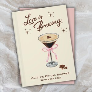 May include: A cream-colored invitation with the text "Love is Brewing" in brown script. It features a watercolor illustration of a coffee cocktail with a pink ribbon and coffee beans. The text "Olivia's Bridal Shower September 2025" is at the bottom.