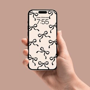 May include: A smartphone with a white background and a black bow pattern. The time is 7:55 and the date is Lunes, 20 de enero.