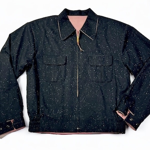 Könnte beinhalten: Eine schwarze Jacke mit Reißverschluss und zwei Pattentaschen. Die Jacke hat ein gesprenkeltes Muster und ein rosafarbenes Futter.