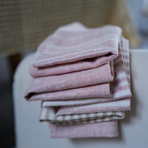 Peut inclure: Une pile de torchons de cuisine en lin rayés rose et blanc. Les torchons sont pliés et empilés les uns sur les autres.