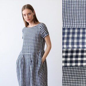 May include: A white and navy blue gingham dress with short sleeves and a boat neck. The dress has a gathered skirt and pockets on the sides.