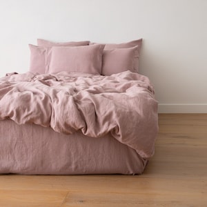 May include: A dusty rose linen duvet cover and pillowcases with a relaxed, wrinkled look. The bedding is arranged on a bed with a matching dusty rose linen bed skirt.