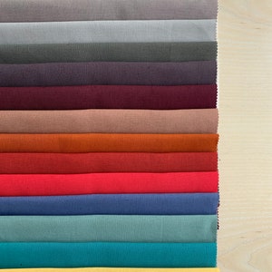 May include: A collection of 15 fabric swatches in various colors, including white, beige, gray, purple, maroon, brown, orange, red, pink, blue, teal, and yellow. The swatches are arranged vertically in a row, with the white swatch at the top and the yellow swatch at the bottom.