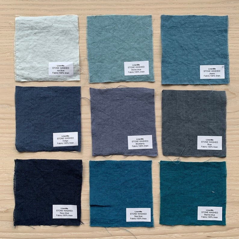 May include: Nine fabric swatches in various shades of blue, from light blue to dark blue. Each swatch has a label with the text "Stone Washed" and the color name, such as "Ice Blue" or "Navy Blue". The fabric is 100% linen.