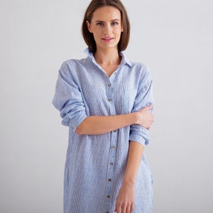Puede incluir: Una mujer con un vestido camisa a rayas azul claro y blanco con cierre de botones.