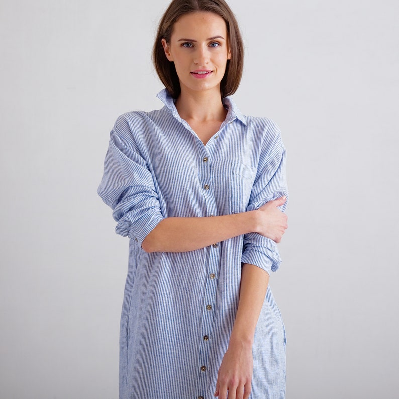 Puede incluir: Una mujer con un vestido camisa a rayas azul claro y blanco con cierre de botones.