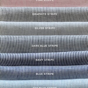 Puede incluir: Siete muestras de tela en diferentes colores y patrones. Las muestras est&aacute;n dispuestas en una pila, con la muestra superior de color rosa con rayas blancas, seguida de gris con rayas blancas, luego plata con rayas blancas, luego azul oscuro con rayas blancas, luego azul marino con rayas blancas, luego azul con rayas blancas, y finalmente azul cielo con rayas blancas. El texto "PINK STRIPE", "GRAPHITE STRIPE", "SILVER STRIPE", "DARK BLUE STRIPE", "NAVY STRIPE", "BLUE STRIPE", y "SKY BLUE STRIPE" est&aacute; impreso debajo de cada muestra.