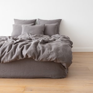 May include: A gray linen duvet cover and pillowcases on a bed with a gray linen bed skirt.