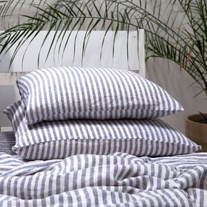 May include: Two blue and white striped linen pillowcases stacked on top of a blue and white striped linen duvet cover.