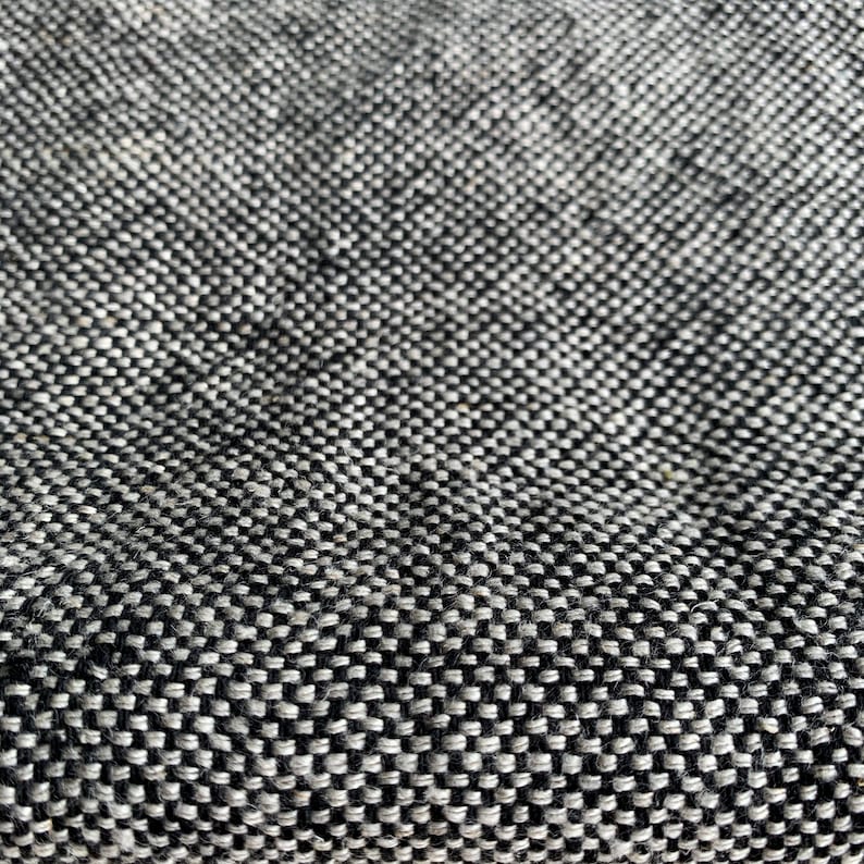 May include: Close-up of a black and white textured fabric with a woven pattern.