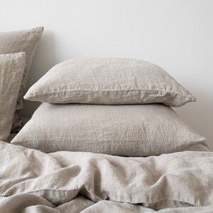 May include: A stack of three beige linen pillowcases. The pillowcases are made of a soft, natural fabric and have a relaxed, casual look.