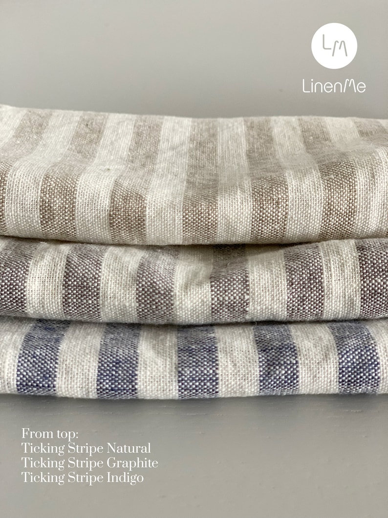 May include: Three fabric swatches stacked on top of each other. The top swatch is a natural ticking stripe, the middle swatch is a graphite ticking stripe, and the bottom swatch is an indigo ticking stripe. The text "From top: Ticking Stripe Natural, Ticking Stripe Graphite, Ticking Stripe Indigo" is below the swatches. The text "LM Linen/Me" is in the top right corner of the image.