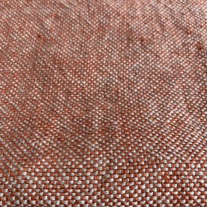 May include: Close-up of a woven fabric with a textured pattern. The fabric is a mix of orange and white threads.