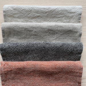 May include: Four fabric swatches in different colors and textures. The top swatch is a light beige linen, the second is a darker beige linen, the third is a black and white tweed, and the bottom is a rust-colored tweed.